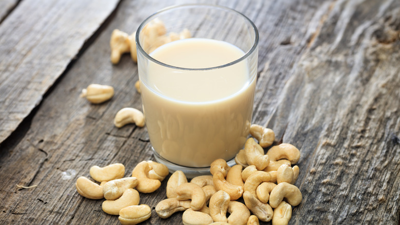 A glass of cashew milk with cashews on table