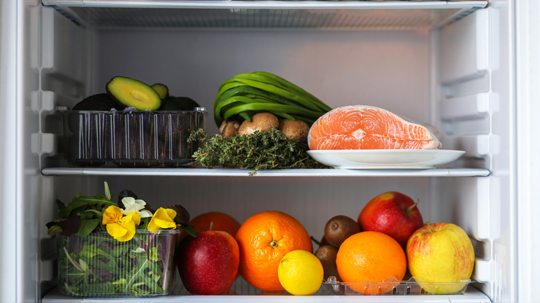 Various fruits, vegetable, and a plate of fish inside a fridge