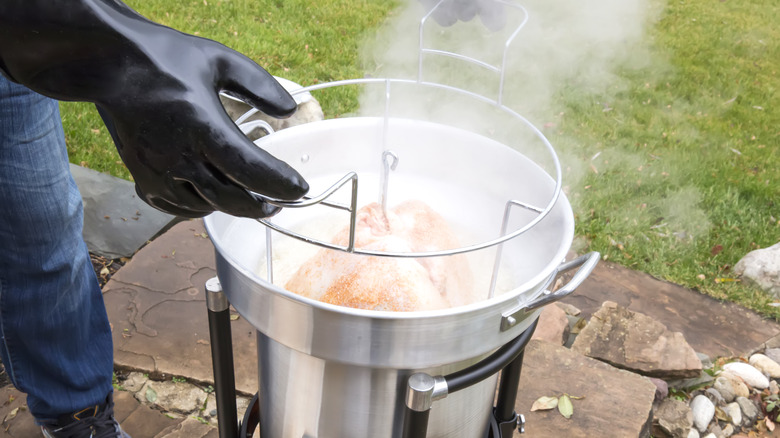 Person deep-frying a whole turkey