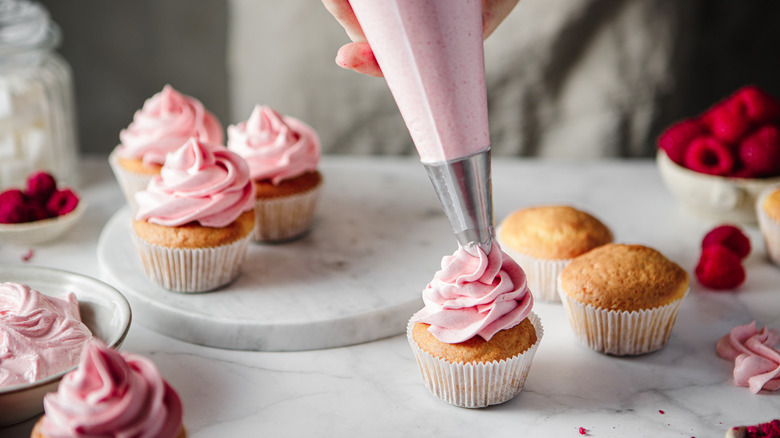 Cupcakes being frosted with a piping bag