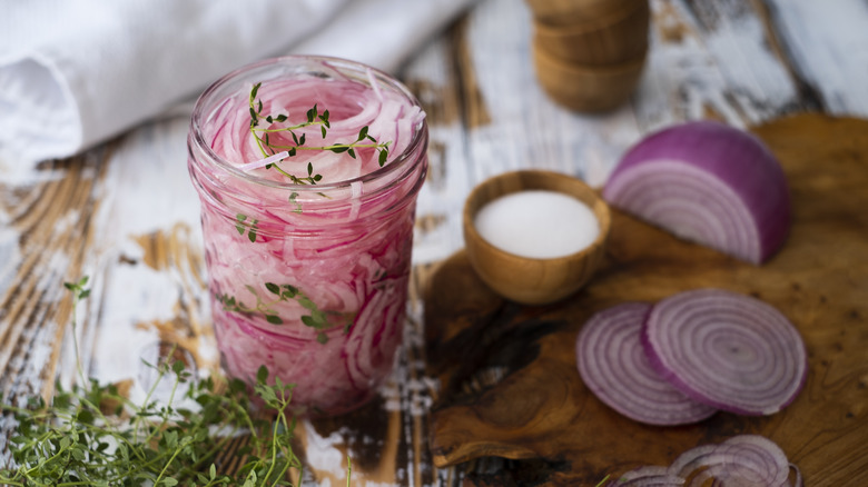 pickled red onions in jar with thyme and salt