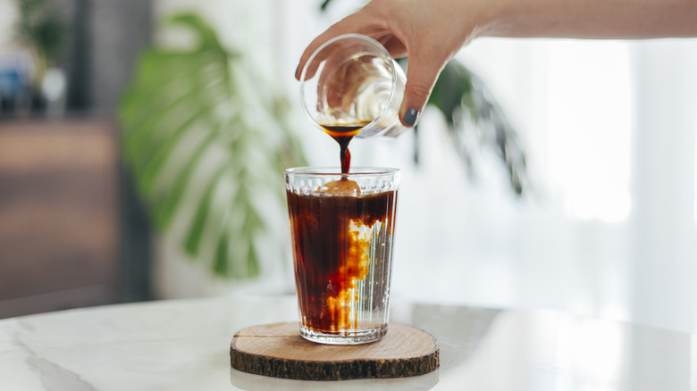Hand pouring cold brew concentrate into water