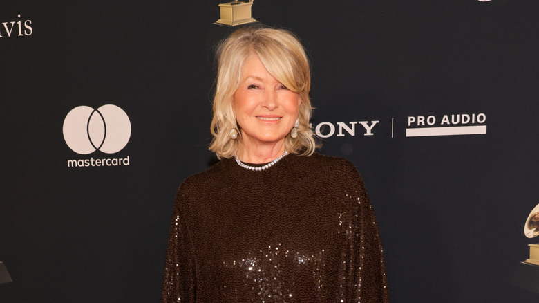 Martha Stewart in a maroon sequined dress with a pearl necklace against a dark backdrop.