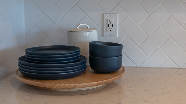 Lazy Susan on a countertop with a white canister and black plates and bowls.