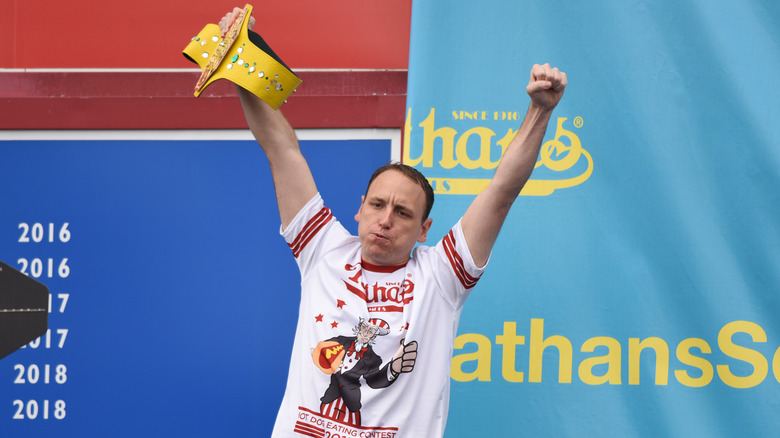 Joey Chestnut holding champions belt
