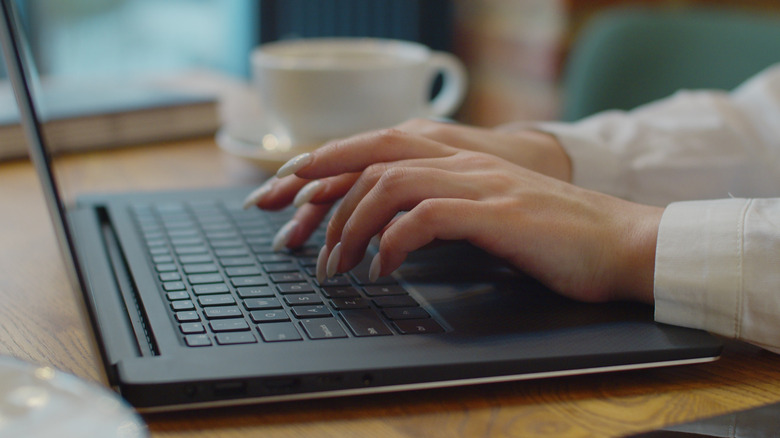 A woman types on her laptop