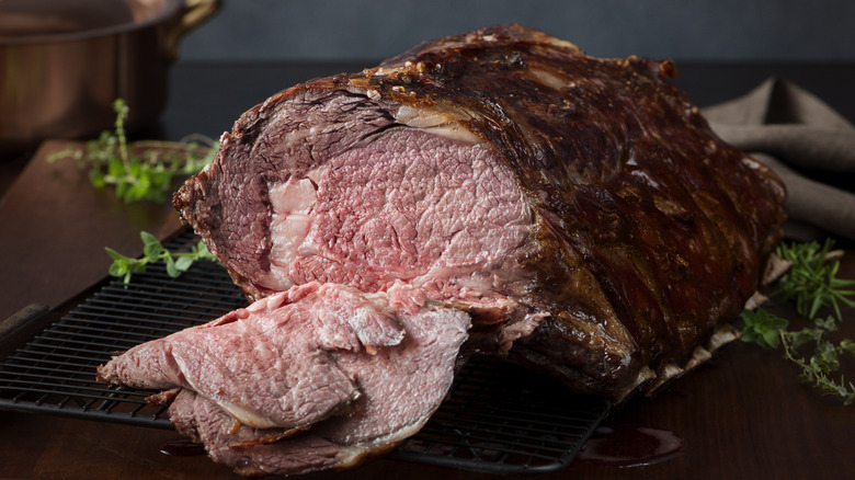 A cooked prime rib roast with an herb garnish