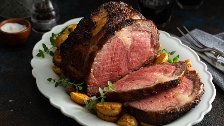 Sliced medium-rare prime rib on a white plate with potatoes