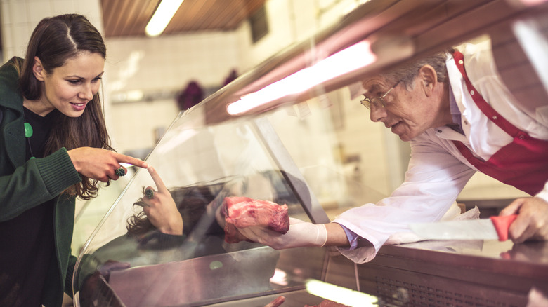 A woman pointing at meat at the butcher shop