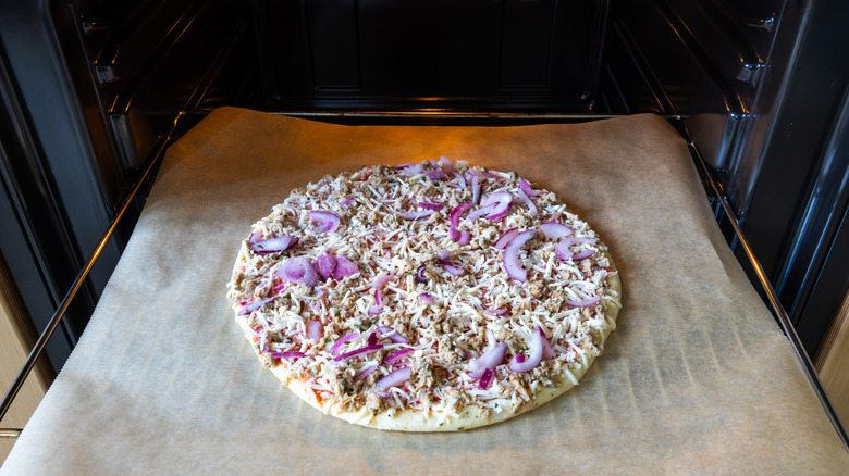 A frozen pizza, about to be put in the oven