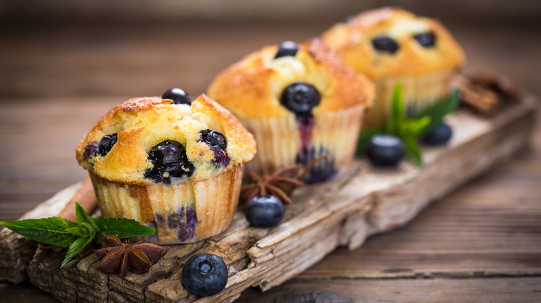 Blueberry muffins lining wooden plank