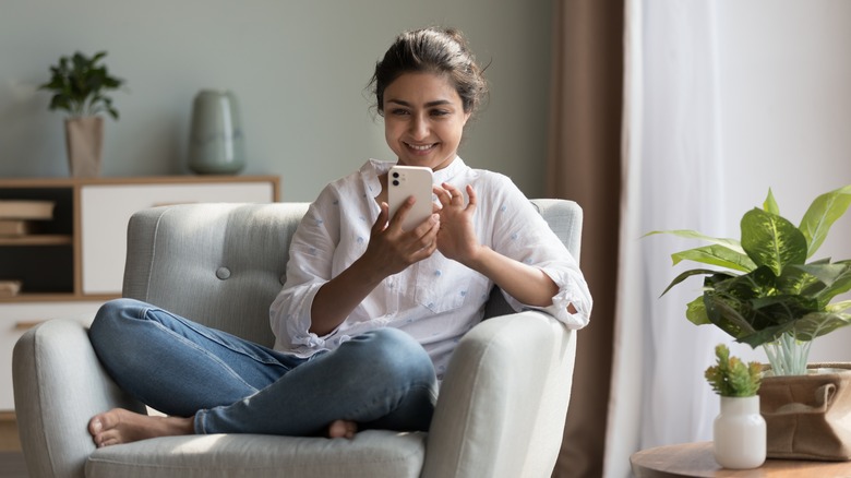 Woman sitting smiling at phone