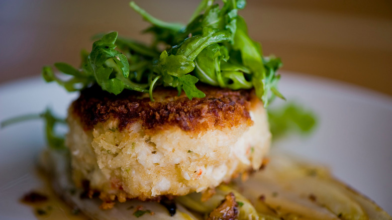 seared crab cake with greens on top