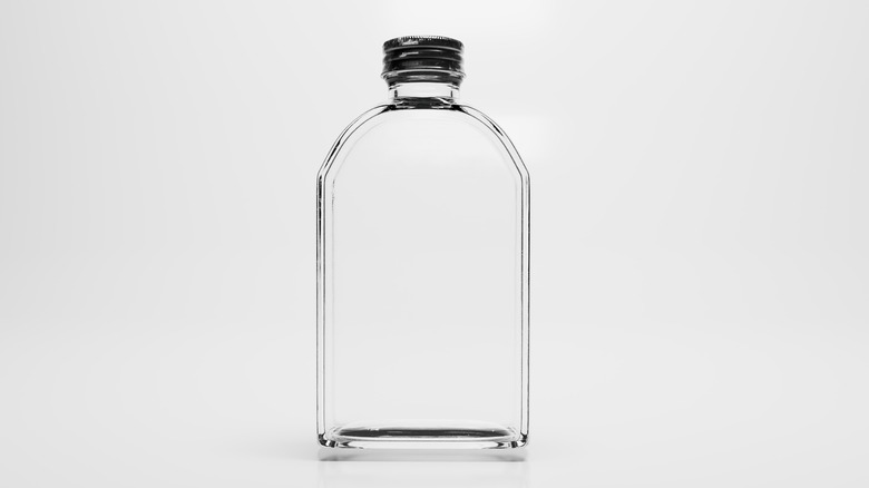 An empty, clear bottle is displayed against a grey background