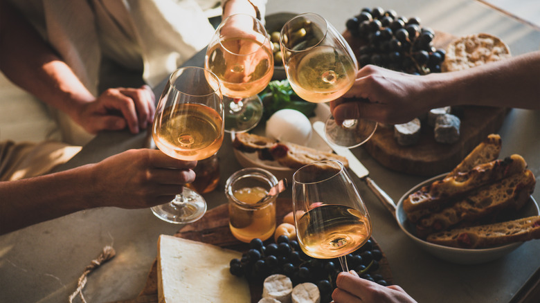 Hands toasting with glasses of white wine