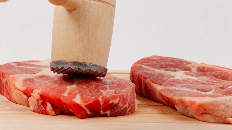 wooden meat mallet hammering meat