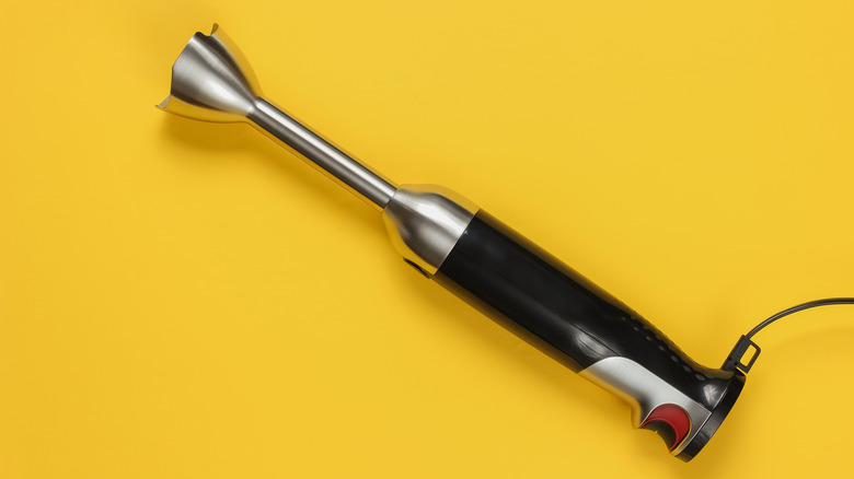 Immersion blender on yellow background