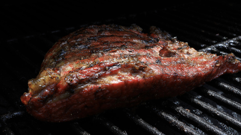 Large piece of beef brisket cooking on grill