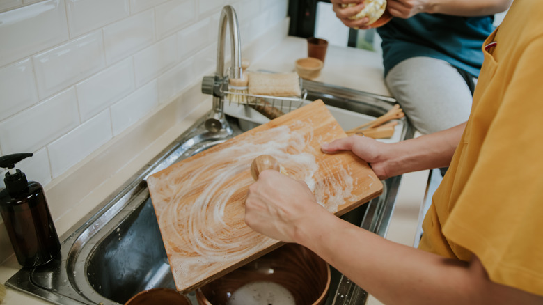 Man washing wooden cutting board