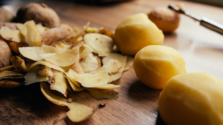 Peeled raw potatoes with discarded peels