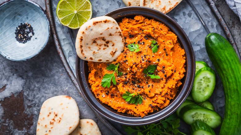 Bowl of carrot dip with vegetables, pita