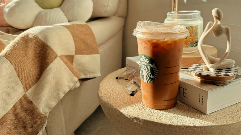 An iced Starbucks pumpkin spiced latte on a small table next to a couch