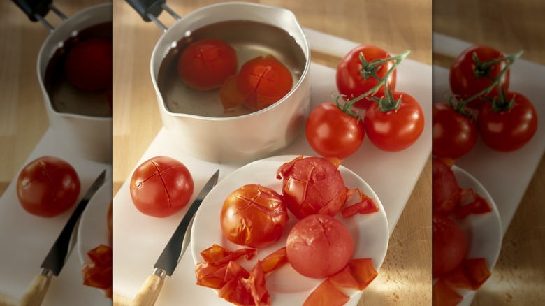 Blanched, partially peeled tomatoes in pot of water and on plate