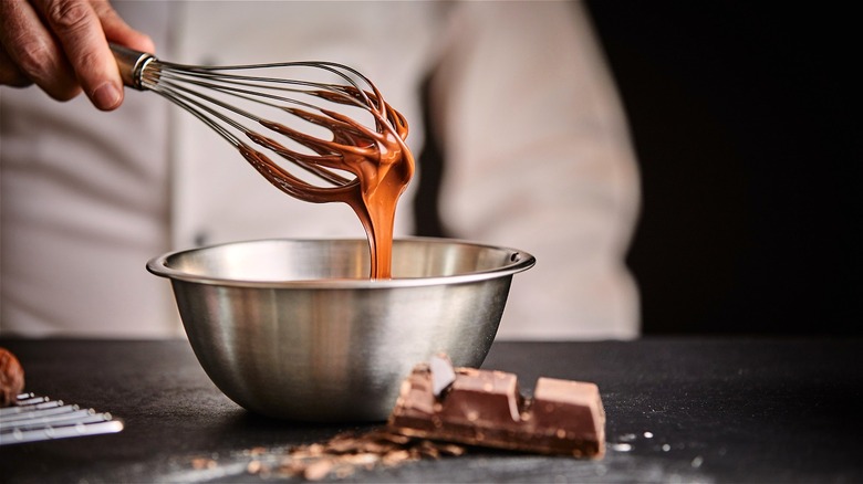person's hand whisking melted chocolate