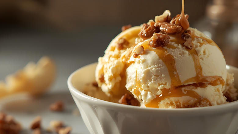 Bowl of ice cream topped with nuts and syrup