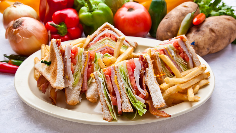 club sandwich with fries on a plate surrounded by veg