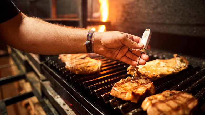 someone checking meat with thermometer