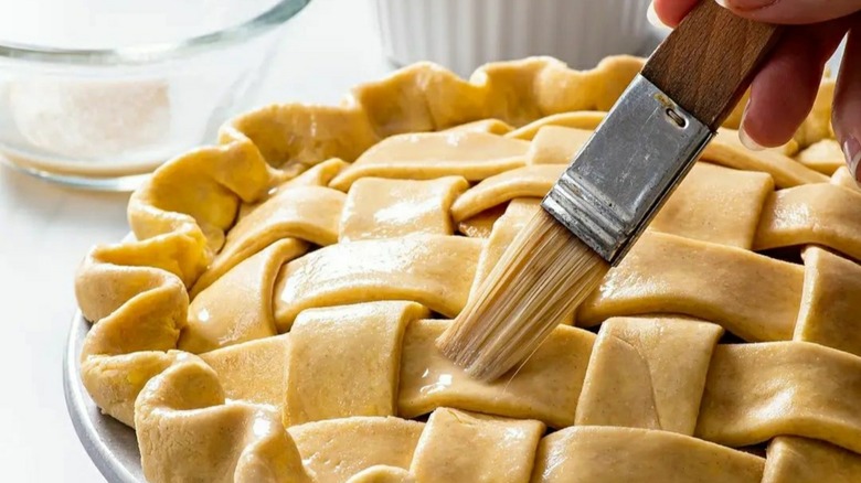 Person brushing pie with pastry brush