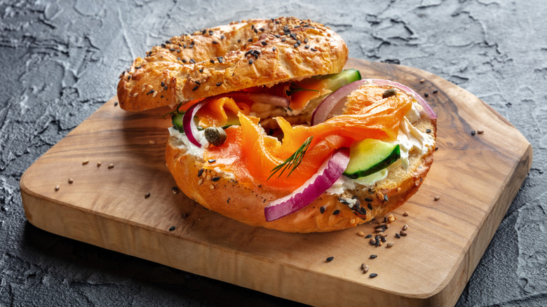 Everything bagel with salmon and veggies on cutting board