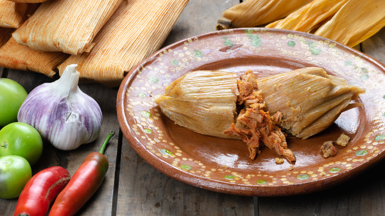 Tamales on plate beside vegetables