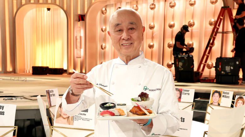 chef nobu matsuhisa holding a plate of sushi