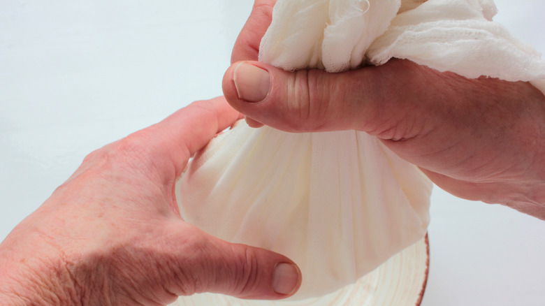 Hands hold cheesecloth over bowl