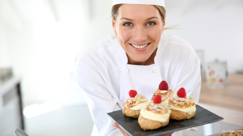 Pastry chef holding a plate of cream puffs
