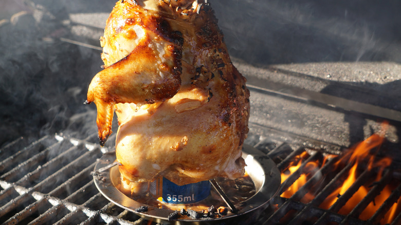 A beer can chicken cooking on a barbeque grill