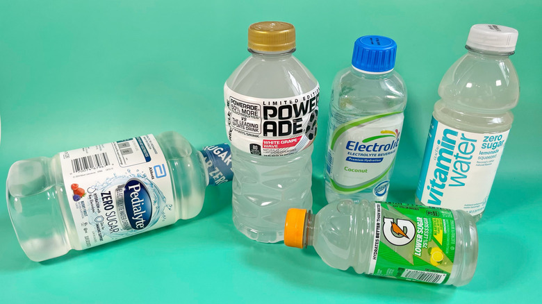 Several clear flavors of different sports drink on a teal background
