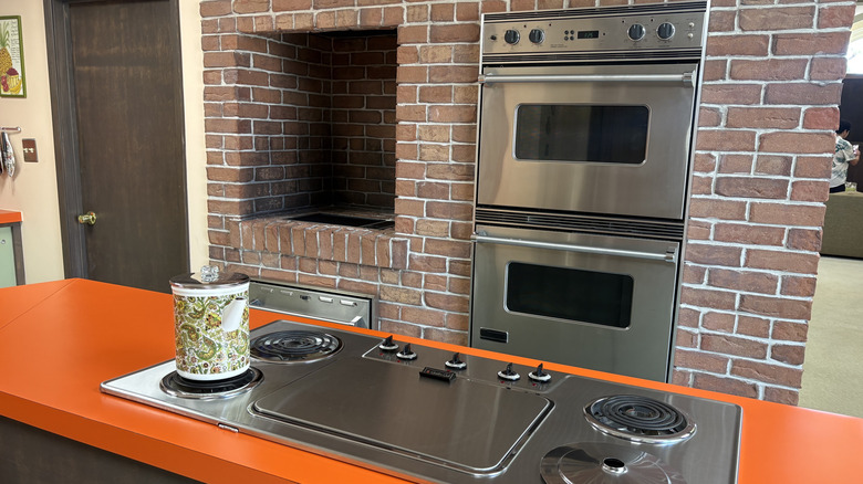 A medium shot of the cooktop and double ovens in the brick wall