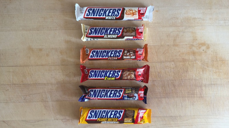 6 different flavors of Snickers bars on wood table