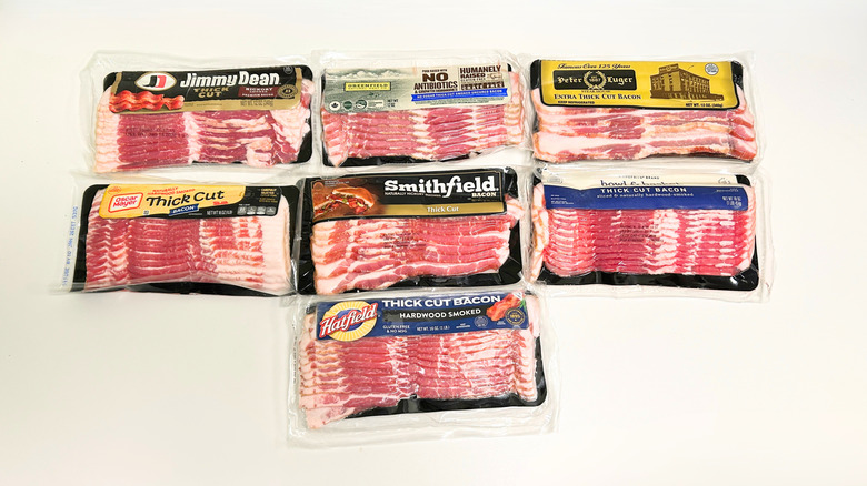 Seven thick cut bacon brands arranged together on a white background