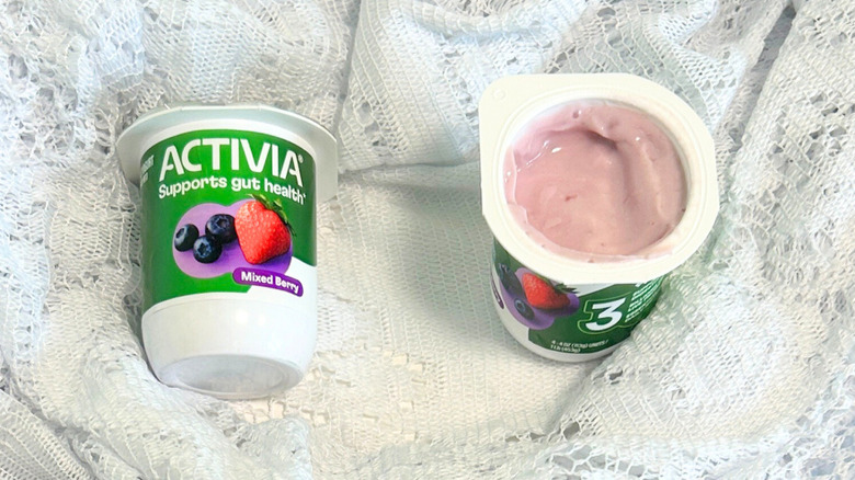 Two containers of Activia Mixed Berry Yogurt on a lacey white background