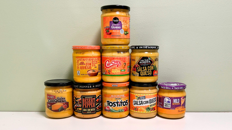 Nine different store-bought queso brands lined up in a pyramid