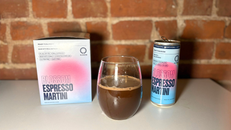 A package of Blossom next to a glass of espresso martini and a can of the drink against a brick backdrop