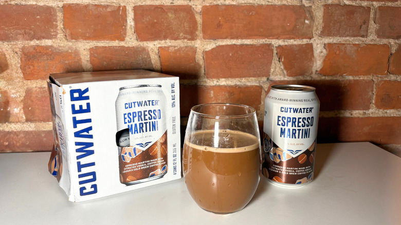 A package of Cutwater next to a glass of espresso martini and a can of the drink against a brick backdrop