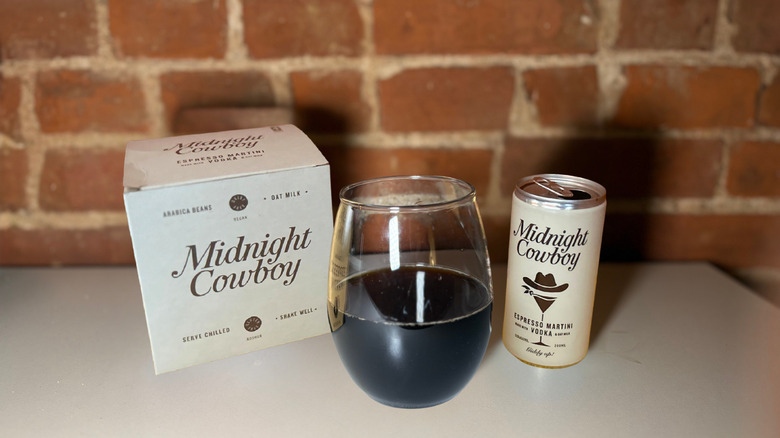 A package of Midnight Cowboy next to a glass of espresso martini and a can of the drink against a brick backdrop