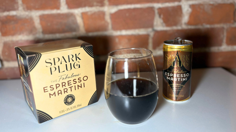 A package of Spark Plug next to a glass of espresso martini and a can of the drink against a brick backdrop