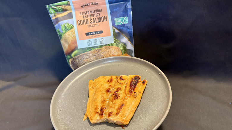 piece of cooked salmon on plate in front of package