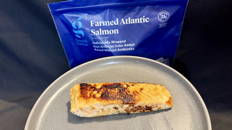 piece of cooked salmon on plate in front of package